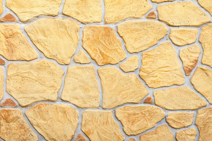 Yellow decorative wall, imitation of uneven concrete stone. Stone Wall Texture. Copy space.